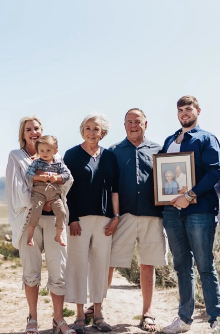 An outdoor group photograph with a child and a framed portrait