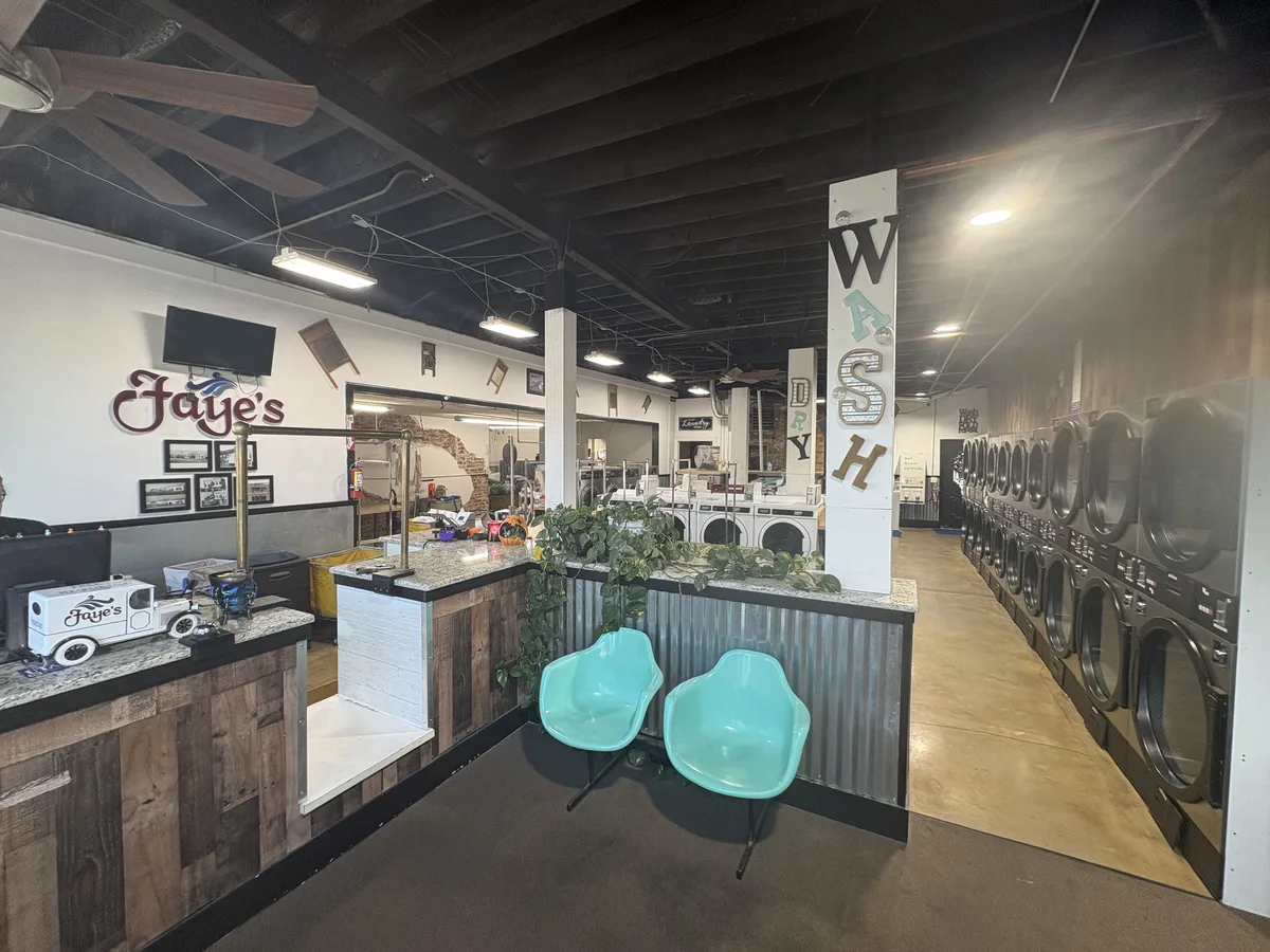Faye's laundromat overview with the service counter and a row of dryers